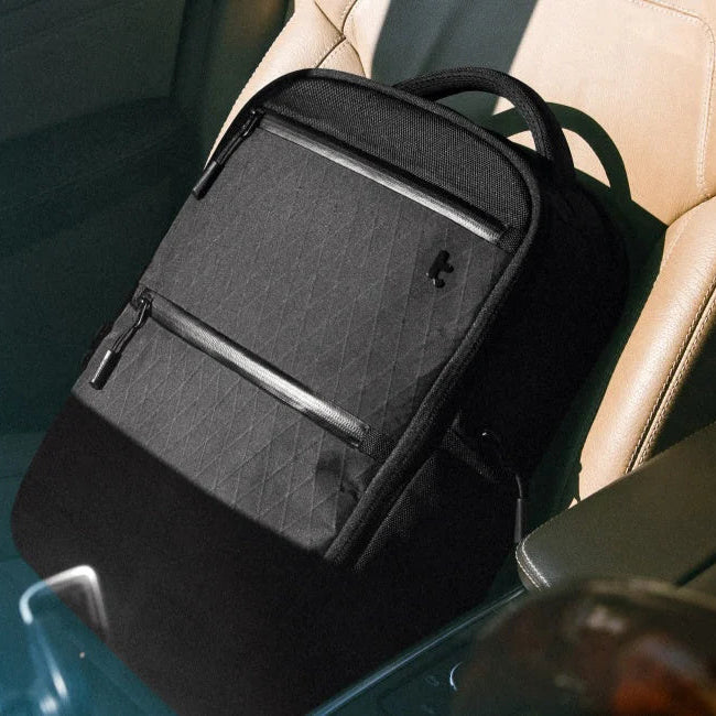 Black backpack on a car seat with a blurred outdoor background