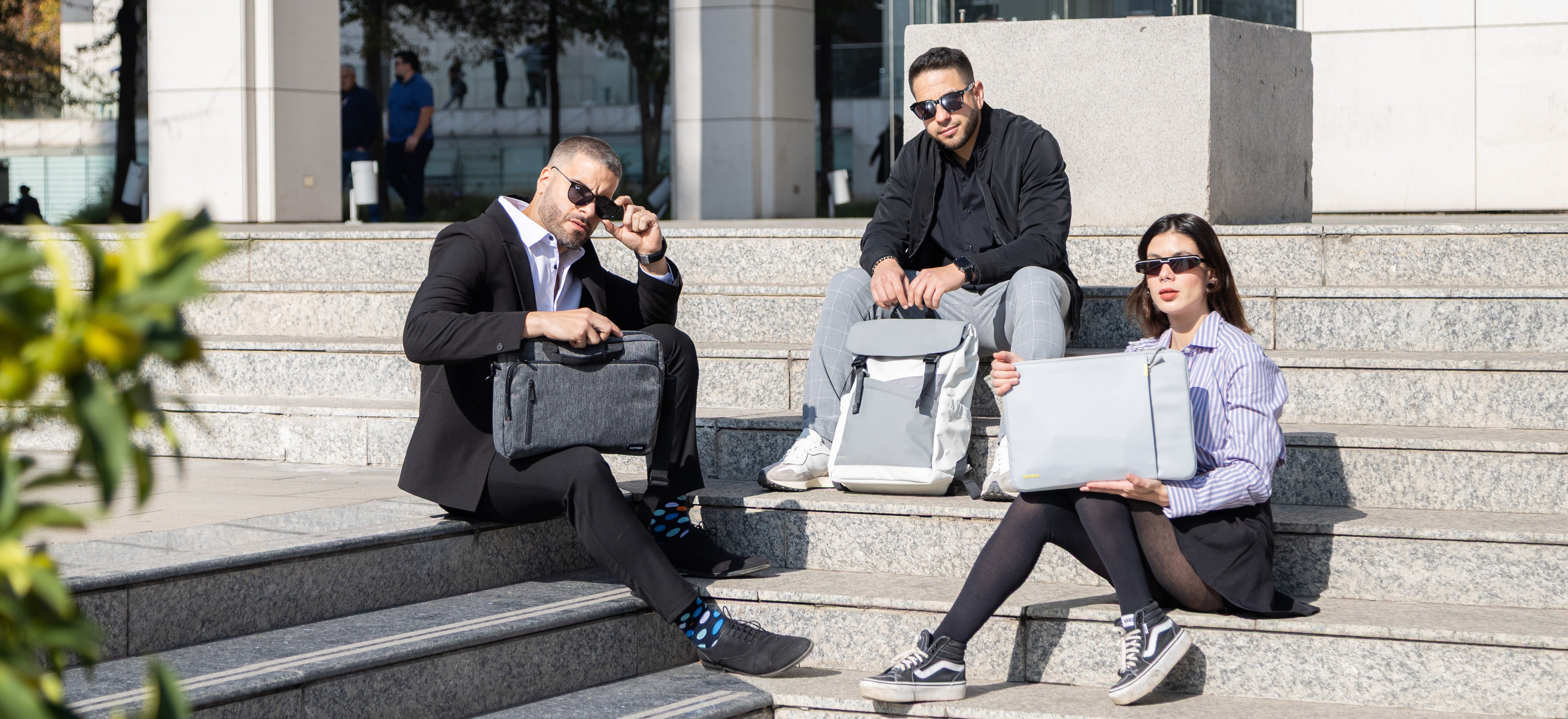 Three professionals sitting on steps outdoors, engaged in work activities.