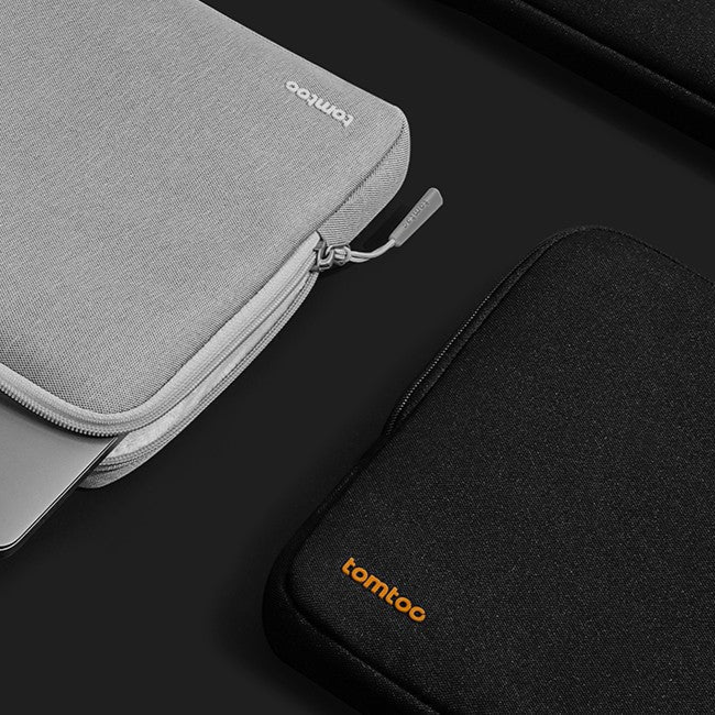 Gray and black laptop sleeves on a dark surface